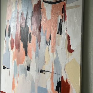 May include: A rectangular canvas painting featuring vertical abstract brushstrokes in shades of peach, light blue, cream, dark red, and black. The textured paint application creates a layered effect across the white background surface.