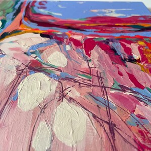 May include: Abstract painting with thick brushstrokes in shades of pink, red, blue, and white. The artwork features large white shapes and textured paint, creating a dynamic and colorful composition. The painting is on a square canvas.