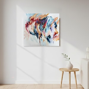 May include: Abstract painting on canvas featuring a profile in shades of red, blue, and orange. The artwork is displayed on a white wall, adding a pop of color to the room. The painting's brushstrokes create a dynamic and expressive composition.