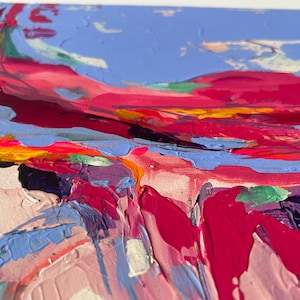 May include: Abstract landscape painting with thick brushstrokes. The artwork features a vibrant color palette of pinks, reds, blues, and yellows. The textured surface creates a sense of depth and movement, evoking a dynamic and expressive feel.