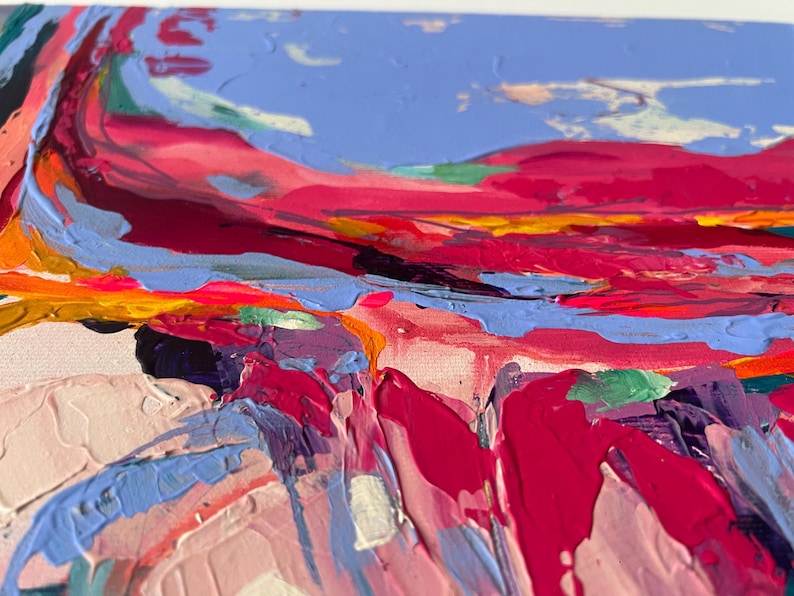 May include: Abstract landscape painting with thick brushstrokes. The artwork features a vibrant color palette of pinks, reds, blues, and yellows. The textured surface creates a sense of depth and movement, evoking a dynamic and expressive feel.