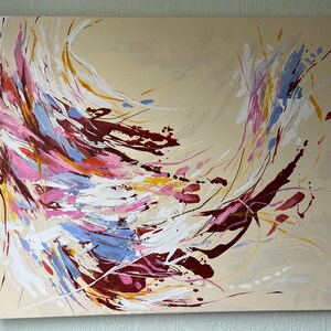 May include: Abstract painting on canvas featuring a swirling composition of colors. The artwork showcases dynamic brushstrokes in shades of burgundy, pink, blue, yellow, and white against a beige background. The piece evokes a sense of movement and energy.