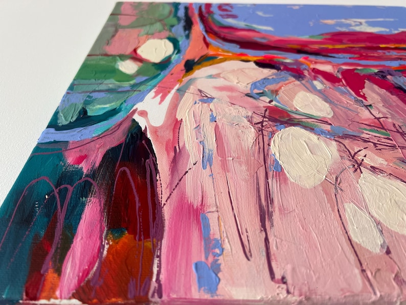 May include: Abstract painting with a palette of pink, teal, and orange. The artwork features thick brushstrokes and textured paint, with white and purple accents. The canvas is viewed from a side angle, showcasing the edges and depth of the piece.