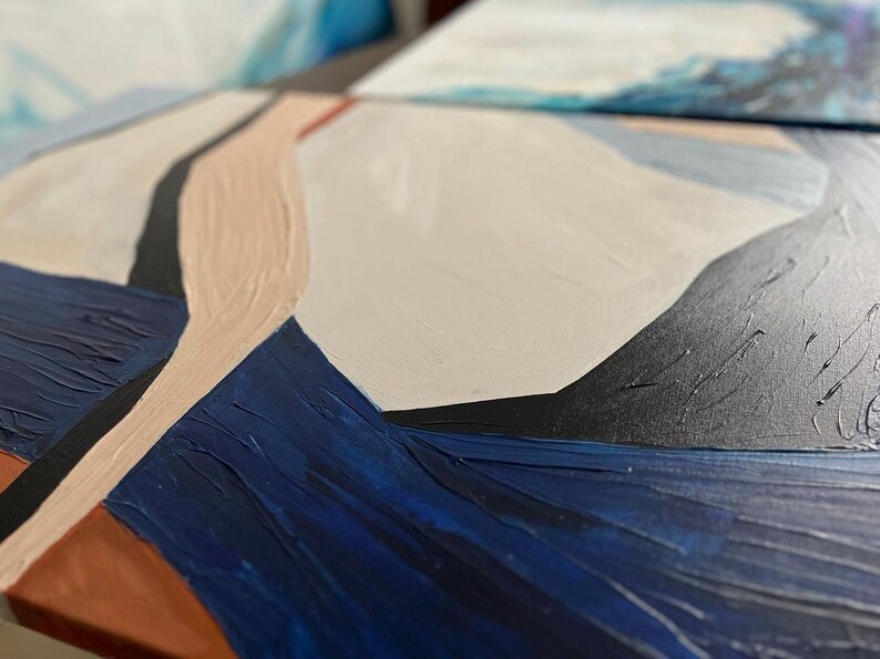 May include: Close-up of an abstract painting with textured brushstrokes. The artwork features a palette of navy blue, beige, black, and white. The composition is geometric, with shapes and lines creating a modern aesthetic. The painting is on a canvas.