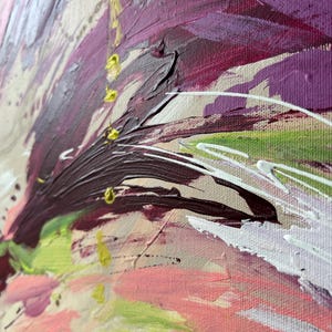 May include: Close-up of an abstract painting with thick brushstrokes. The artwork features a palette of colors including deep purple, pink, green, and white, applied on a beige canvas. The texture is rich and the style is expressive.
