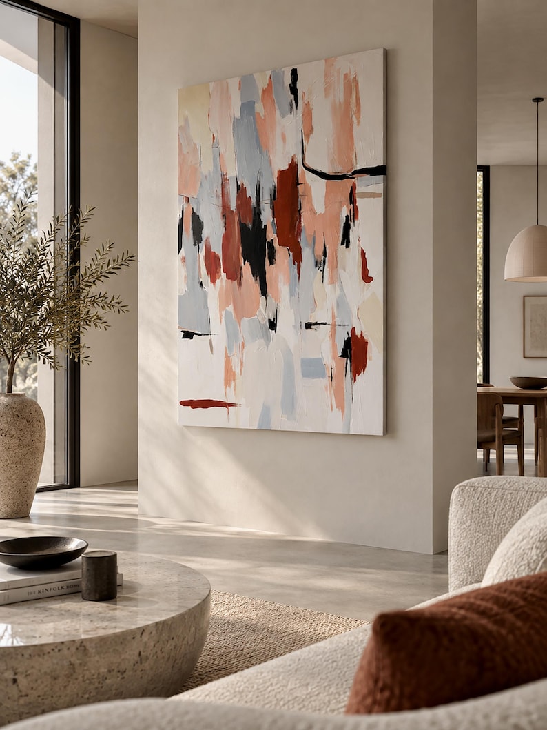 May include: A large rectangular canvas painting featuring an abstract composition of vertical brushstrokes in shades of terracotta, soft peach, light grey, cream, and bold black accents, displayed on a neutral wall in a bright living space.