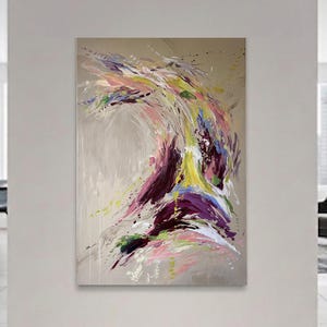 May include: Abstract painting with a beige background and a dynamic composition of colorful brushstrokes. The artwork features vibrant hues of purple, yellow, pink, and green, creating a sense of movement and energy. The painting is displayed in a modern living space.