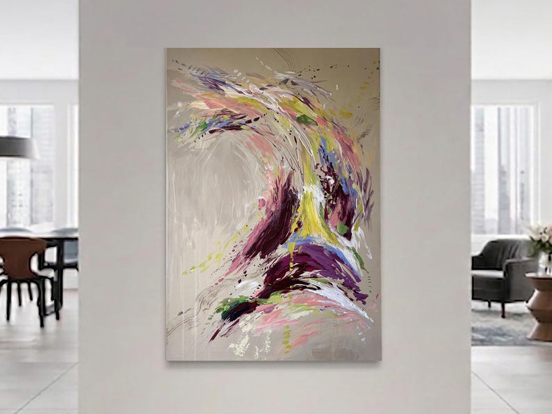May include: Abstract painting with a beige background and a dynamic composition of colorful brushstrokes. The artwork features vibrant hues of purple, yellow, pink, and green, creating a sense of movement and energy. The painting is displayed in a modern living space.