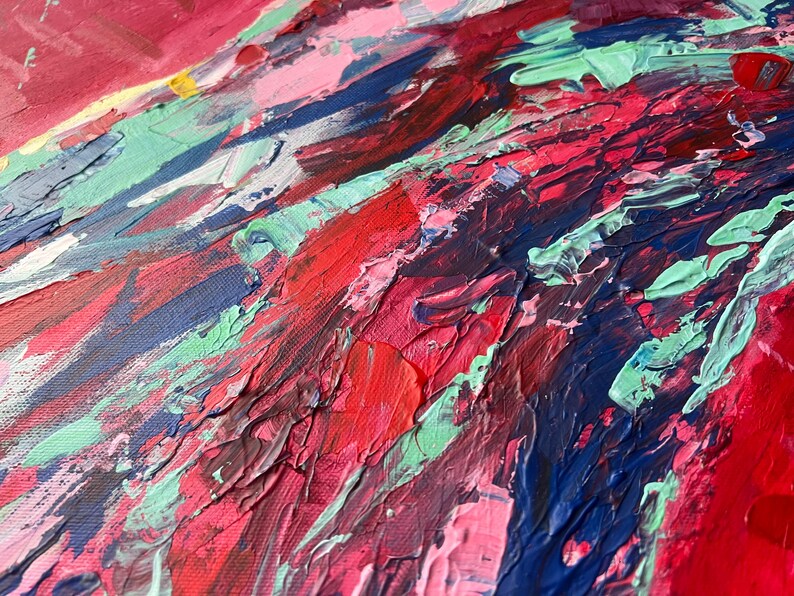 May include: Close-up of an abstract painting with thick brushstrokes. The artwork features a vibrant mix of colors, including shades of red, pink, blue, and green. The textured surface creates a dynamic and expressive visual effect, suggesting a modern art style.