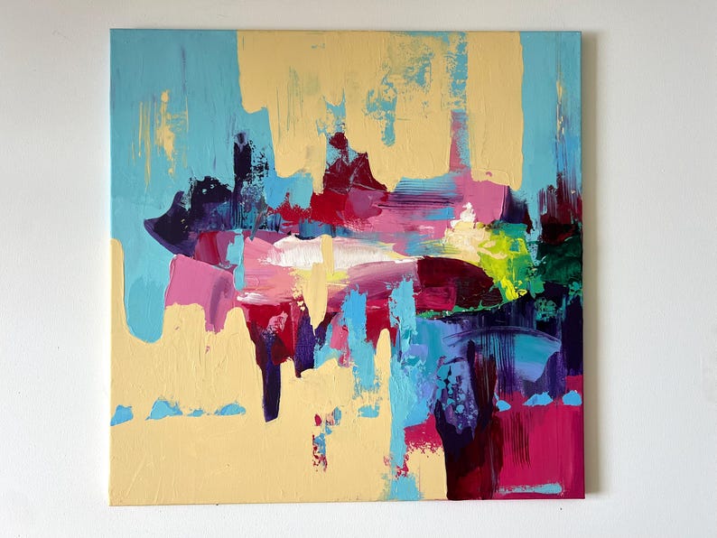 May include: Abstract painting with a square canvas. The artwork features a blend of colors, including light blue, yellow, pink, red, purple, and green. The brushstrokes are visible, creating a textured effect. The painting is mounted on a white wall.