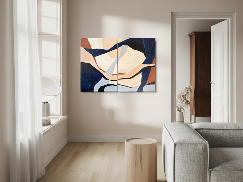 May include: Abstract art piece composed of two panels. The artwork features a blend of colors, including navy blue, beige, and rust. The design showcases organic shapes and forms, creating a modern and artistic aesthetic. The artwork is displayed in a living room setting.