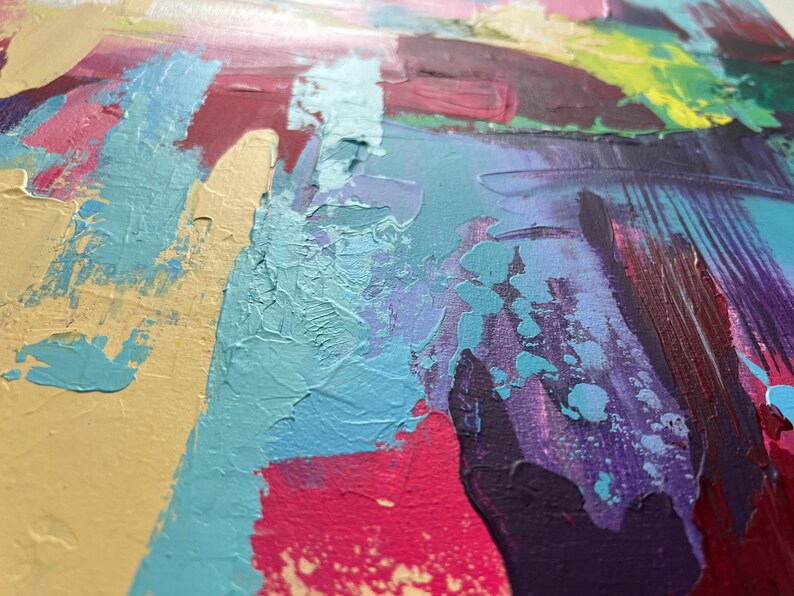 May include: Abstract painting with thick brushstrokes in shades of yellow, teal, pink, purple, and green. The textured surface shows the layering of paint, creating a dynamic and colorful artwork. The artwork is a close-up view of the painting.