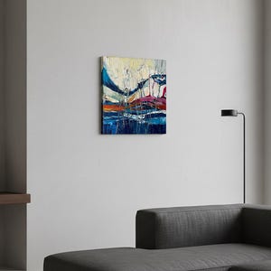 May include: Abstract oil painting on canvas. The artwork features a vibrant composition of blues, oranges, and whites, with bold brushstrokes creating a textured effect. The painting is mounted on a white wall.
