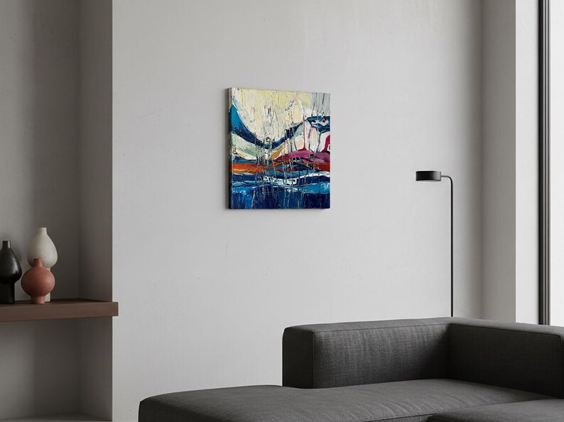 May include: Abstract oil painting on canvas. The artwork features a vibrant composition of blues, oranges, and whites, with bold brushstrokes creating a textured effect. The painting is mounted on a white wall.