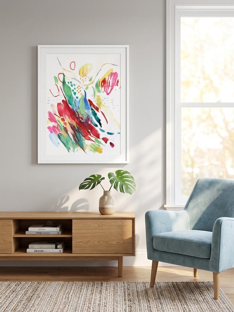 May include: A framed abstract wall art print featuring vibrant brushstrokes in red, blue, green, and yellow on a white background. The artwork is displayed in a simple white frame, showcasing dynamic, expressive paint marks and colorful shapes.