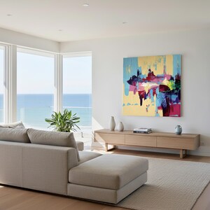 May include: A modern living room with a beige sectional sofa, a light wood media console, and a large abstract painting with blue, yellow, and red hues. The room has large windows overlooking the ocean.
