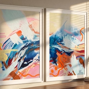 Puede incluir: Dos l&aacute;minas de arte mural rectangulares enmarcadas con pinceladas abstractas en tonos azul, rosa, naranja y blanco. La obra muestra texturas de pintura superpuestas con l&iacute;neas audaces y formas org&aacute;nicas, dentro de marcos blancos delgados.