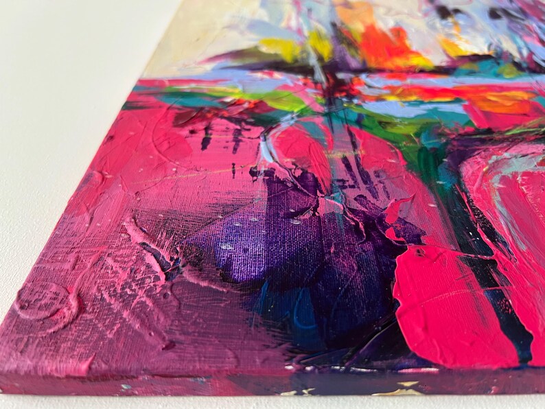 May include: Close-up of an abstract painting with thick brushstrokes. The artwork features a vibrant palette of pink, purple, orange, blue, and green hues. The textured surface of the canvas is visible, showcasing the artist's technique and use of color.