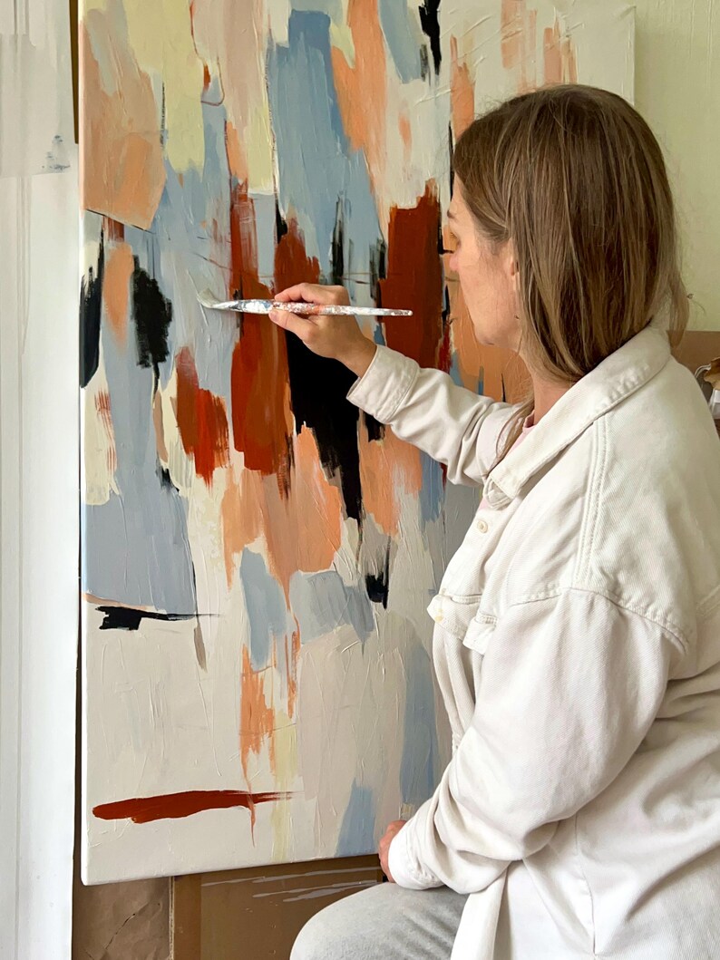 May include: A large rectangular canvas featuring an abstract painting with vertical brushstrokes in shades of terracotta, light blue, cream, and black. The composition displays layered paint textures and bold colour blocks applied across the surface.