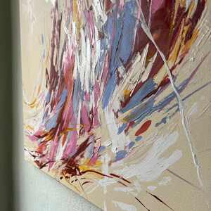 May include: Abstract painting with a beige background and bold brushstrokes in shades of red, pink, blue, white, and yellow. The artwork features a textured surface with visible paint layers, creating a dynamic and expressive composition.
