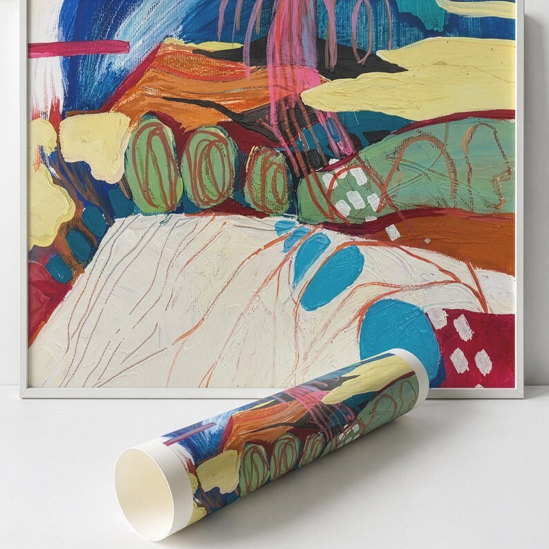May include: A framed abstract painting featuring vibrant layers of blue, yellow, orange, green, and pink paint with visible brushstrokes and linear markings. A rolled print of the same artwork is positioned in front of the framed piece.