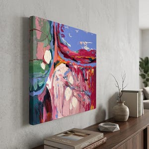 May include: Abstract art canvas with a vibrant mix of colors. The artwork features bold brushstrokes in shades of red, pink, blue, and green. The canvas is mounted on a wooden frame and displayed on a gray wall.