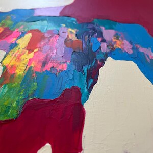 May include: Abstract artwork with bold brushstrokes in a variety of colours. The painting showcases pink, yellow, green, blue, and purple shades, with deep red accents set against a neutral backdrop. The textured paint creates a dynamic visual effect.
