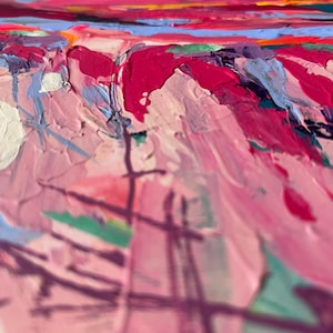 May include: Close-up of an abstract painting with thick brushstrokes. The artwork features a palette of pinks, reds, blues, and yellows. The texture is heavily layered, creating a sense of depth and movement. The style is impressionistic.