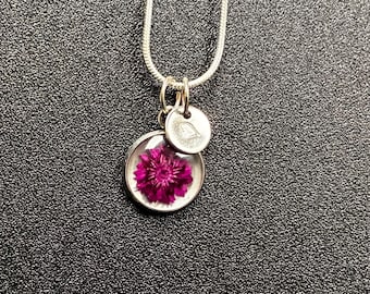Personalisierte Halskette mit Initial-gestempelten Wildblumen-Harz-Anhänger an der Silberkette.