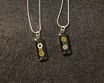 Auffallende schwarze minimalistische Harzanhänger mit silber- und goldfarbenen Zahnrädern im Steampunk-Stil.