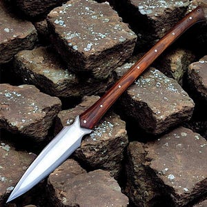 May include: A spear with a polished steel blade and a dark wood handle. The handle is accented with small silver rivets. The spear is approximately 152 cm long.
