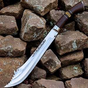 May include: A machete with a curved silver steel blade featuring a serrated tip and a series of small circular cutouts along the spine. The handle is crafted from dark brown wood with a decorative gold and black patterned band near the bolster.