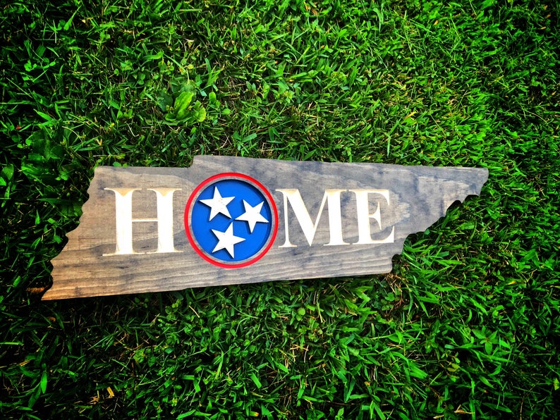 May include: Wooden sign shaped like the state of Tennessee with the word "HOME" in white lettering and a blue circle with three white stars in the centre. The circle has a red outline.