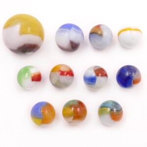May include: A collection of colorful glass marbles of various sizes. The marbles feature a mix of colors including yellow, blue, green, red, and orange, with swirled and segmented patterns. The marbles are arranged on a white surface.