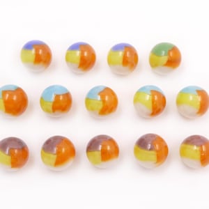 May include: Fifteen colorful glass marbles with a mix of orange, yellow, blue, green, and purple segments. Each marble has a white base and is arranged on a white background.
