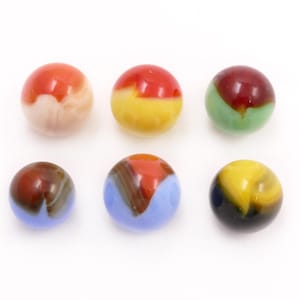 May include: Six colorful glass marbles with various designs. The marbles feature a mix of colors, including red, yellow, blue, green, and brown. The marbles are round and have a glossy finish, perfect for collectors or game enthusiasts.