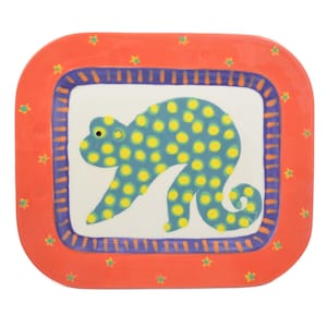 May include: A square ceramic plate with a playful design. The plate features a blue monkey with yellow polka dots on a white background, framed by a purple border and an orange outer edge with green star accents. A whimsical and colorful piece.
