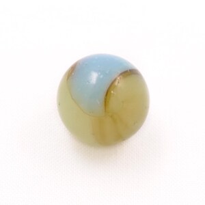 May include: A spherical glass marble featuring a translucent pale olive green base color with a distinct opaque light blue swirl pattern that wraps around the upper portion of the surface, creating a smooth and glossy finish on the object.