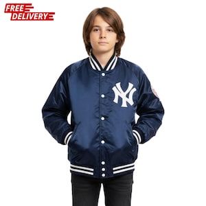 May include: A navy blue satin bomber jacket with white accents and the New York Yankees logo. The jacket has a snap-front closure, pockets, and striped cuffs and hem. The jacket is worn by a person.