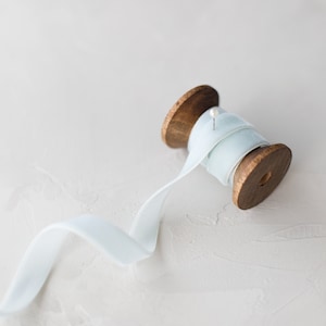 May include: A wooden spool of light blue ribbon with a pin holding the ribbon in place.