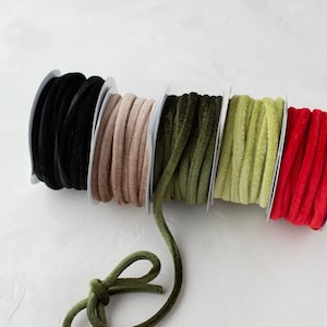 May include: Five spools of velvet ribbon in black, beige, dark green, light green, and red.