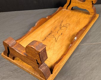 May include: A rectangular wooden serving tray with a medium brown finish. The tray features carved, stylised horse-shaped handles at both ends and a scalloped edge along the sides. A black line drawing of a dog is etched into the centre of the tray.