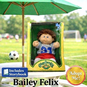 May include: A Cabbage Patch Kids doll named Bailey Felix, in its original box, is displayed under a green umbrella. The doll wears a gray and blue jersey with the number 91 and red shorts. A soccer ball is in the background.