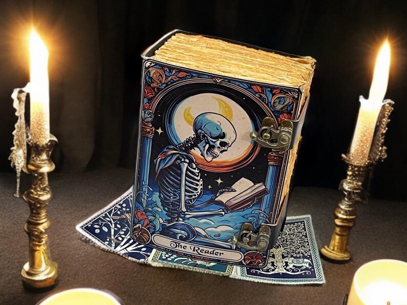 Peut inclure: Un livre rectangulaire avec une couverture en m&eacute;tal illustr&eacute;e d'un squelette lisant sous un croissant de lune. La couverture porte l'inscription The Reader. Le livre pr&eacute;sente des pages jaunies et est ferm&eacute; par deux loquets en laiton vieilli.