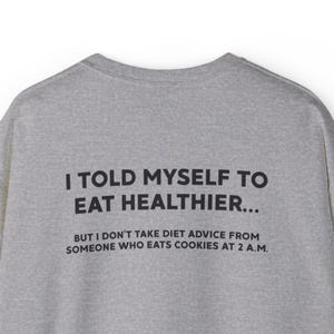 May include: A grey sweatshirt with black text. The text says, "I TOLD MYSELF TO EAT HEALTHIER... BUT I DON'T TAKE DIET ADVICE FROM SOMEONE WHO EATS COOKIES AT 2 A.M."