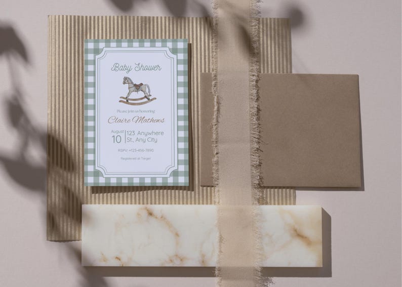 May include: A baby shower invitation with a green gingham border and a rocking horse illustration. The invitation includes the text "Baby Shower" and event details. A brown envelope and decorative elements complete the scene.