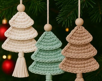 May include: Three handmade crochet Christmas tree ornaments in cream, mint green, and tan, each with a wooden bead and tassel. The text "Digital crochet pattern" is in a white circle. The ornaments hang against a backdrop of evergreen branches.
