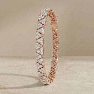 May include: Rose gold bracelet with a geometric design. The bracelet features triangular sections encrusted with small, sparkling white stones. The clasp is visible on the right side, and the bracelet is set against a neutral background.