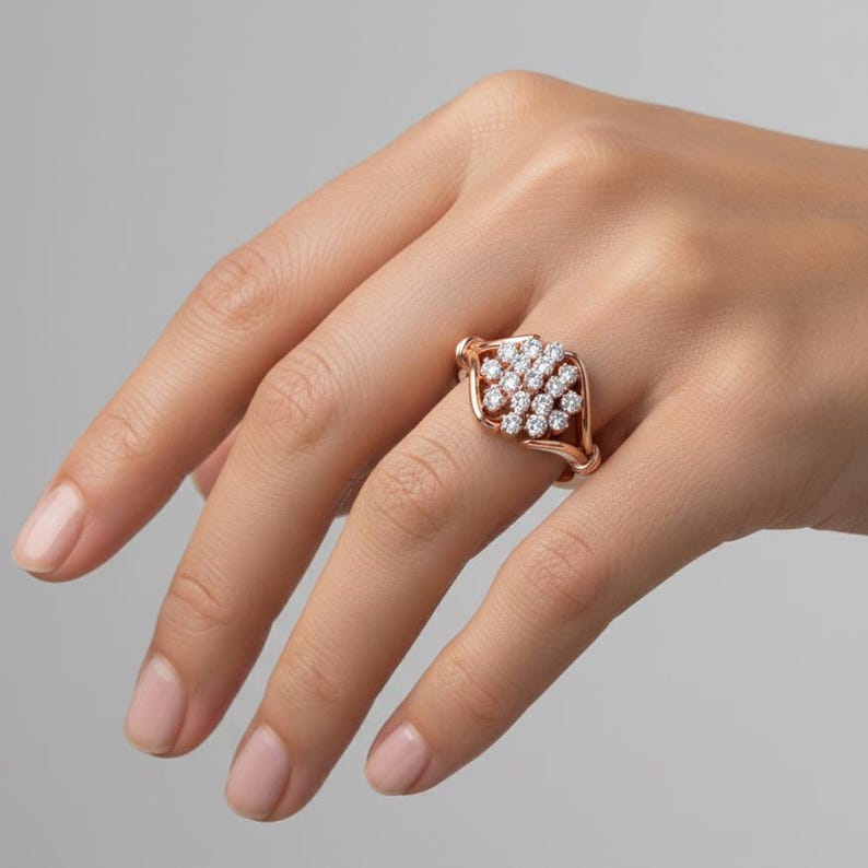 K&ouml;nnte beinhalten: Ein ros&eacute;goldener Ring mit einem Cluster aus kleinen, runden, klaren Edelsteinen. Der Ring hat ein offenes, gewebtes Design um das Edelsteincluster. Der Ring wird an einer Hand gezeigt.