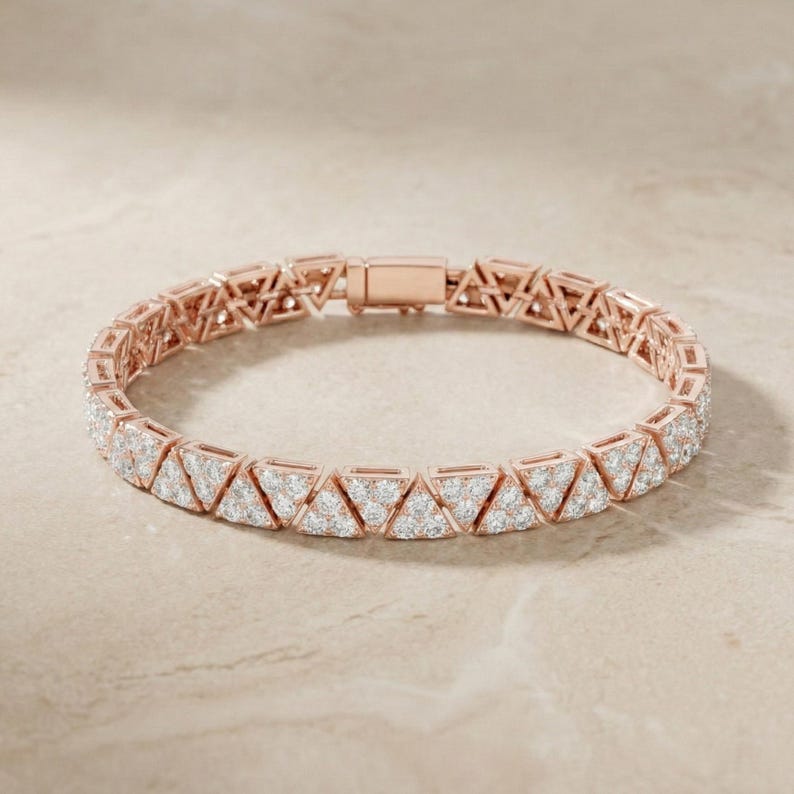 May include: Rose gold bracelet featuring a repeating pattern of triangular shapes, each encrusted with small, sparkling stones. The bracelet has a secure clasp closure and is displayed on a neutral background.